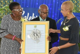 Minister of Education and Youth, Hon. Fayval Williams (right), and Acting Vice Principal, Shortwood Teachers’ College, Dr. Claudette Barrett-March (left), present Dr. Lincoln Phipps with a citation for 27 years of service of the college. Occasion was an appreciation ceremony for outstanding service, held at the institution in Kingston on Wednesday (November 23).