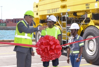 Prime Minister, the Most Hon, Andrew Holness (left), engages with Straddle Carrier Operator, Samuel Black (centre) and Electrical Engineer, Cherrissa Allen, during the ribbon cutting for the new Kingston Freeport Terminal Limited (KFTL) straddle fleet, valued at more than US$20 million, at the container port on Thursday (November 3).