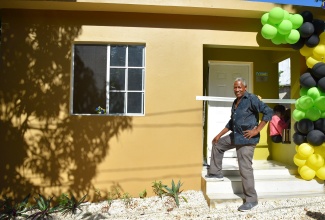 Recipient, Flazel Jackson, poses in front of his new home in Norwood, St. James, that was provided under the New Social Housing Programme (NSHP). Prime Minister, the Most Hon. Andrew Holness, presented him with the keys on Friday (November 25). 