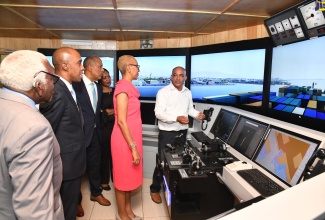 Minister of Education and Youth, Hon. Fayval Williams (second right), looks on as Simulator Instructor, Caribbean Maritime University (CMU), Derrick McLennon (right), explains the features of the stimulator used in maritime training, during a tour of the university in Kingston on Tuesday (December 6). Others (from left) are former Speaker of the House of Representatives, Pearnel Charles; President, CMU, Professor Andrew Spencer; Chairman, CMU, Professor Gordon Shirley; and Manager, Corporate Communication and Public Relations, Ministry of Education and Youth, Sheryl Bromfield. 

