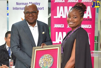 Minister of Tourism, Hon. Edmund Bartlett (left), presents the Chairman’s Award to Commercial Manager, Norman Manley International Airport (NMIA) Limited, Kaydian Dawes-Wynter. Occasion was an appreciation ceremony for the NMIA team on Tuesday (December 20), at the NMIA in Kingston.