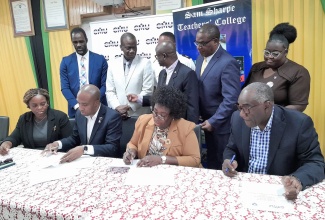 Caribbean Maritime University (CMU) President, Professor Andrew Spencer (second left, seated) and Principal of Sam Sharpe Teachers’ College (SSTC),  Dr. Lorna Gow-Morrison (second right, seated), sign a Memorandum of Understanding (MOU) for SSTC to formally accommodate the western campus of the CMU. The signing took place at the College on December 8.  Also participating in the signing (from left) are Vice Principal, Administration and Registrar,  CMU, Keisha Walker and Chairman, Board of Governors, SSTC, Norman Reid. 