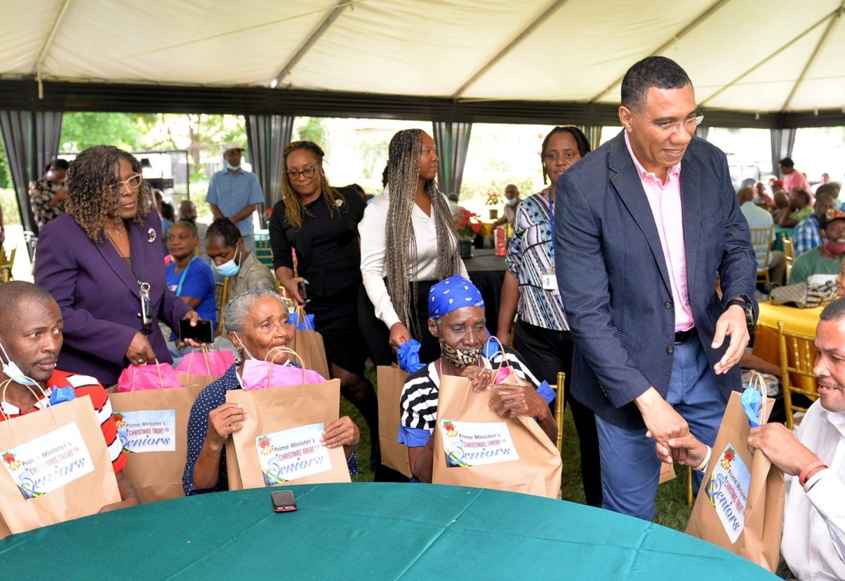 Prime Minister, the Most Hon. Andrew Holness (second right), greets a resident of the Marie Atkins Night Shelter. Looking on are other residents of the facility who also received gift packages from the Prime Minister. The occasion was the Office of the Prime Minister (OPM) end-of-year senior citizens treat. The event was held on the lawns of the OPM, on Wednesday (December 14).