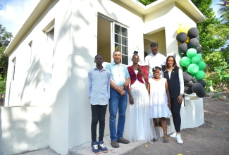 Prime Minister, the Most Hon. Andrew Holness (second left) joins  Naderia Wood (third left), and her children (from left), Romeo Smith, Jordan Coley and Shaheim Dunn, in front of their new three-bedroom home in New Hall district in  Manchester Central on Friday (Dec.16). Occasion was the official hand over of the unit provided under the New Social Housing Programme (NSHP).  Sharing the moment is Member of Parliament for the area, Rhoda-Moy Crawford.