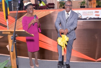 Pastor Leroy Laing of the Pentecostal Tabernacle on Wildman Street, has a light moment as he demonstrates the use of one of two pitch forks donated to the church by the Ministry of Agriculture and Fisheries. At left is Senior Director (Actg.), Agriculture and Land Division in the Ministry, Pamela McKenzie. Occasion the World Soil Day Church Service at  the church in Kingston on Sunday ( Dec. 4).

