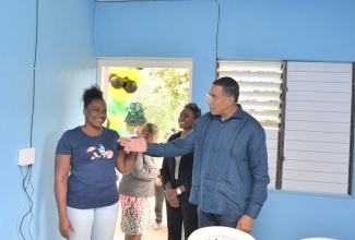 Prime Minister, the Most Hon. Andrew Holness (right), engages with beneficiary under the Government’s New Social Housing Programme (NSHP), Marsha Brown (left), during a recent handover ceremony in Stony Hill, St. Andrew. Sharing the moment is Member of Parliament for St. Andrew West Rural, Hon. Juliet Cuthbert-Flynn (second right).

