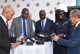 Minister of National Security,  Hon. Dr. Horace Chang (right), inspects a Traffic Ticket Management System (TTMS) handset. Event was the handover of 750 TTMS handsets and 750 mobile handheld printers to the Jamaica Constabulary Force (JCF), today (January 19), at the Office of the Commissioner of Police, St. Andrew. Also examining the devices (from left) are Commissioner of Police, Major General Antony Anderson; Minister of State in the Ministry, Hon. Zavia Mayne; Senior Director, Major Technology Transformation Branch in the Ministry, Emil Holgate and Woman Constable, Morata Murdoch, who demonstrated the use of the devices.