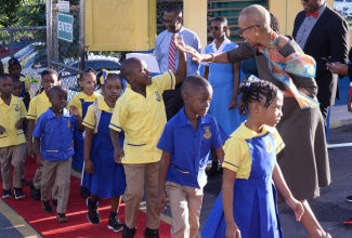 Minister of Education and Youth, Hon. Fayval Williams (right), high-fives a young student of the Constant Spring Primary and Junior High School, in Kingston, on the opening day of the new school term, on Monday (January 9). 