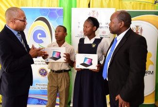 Chief Executive Officer of e-Learning Jamaica Company Limited, Andrew Lee (left), shares in conversation with (from second left) student at Greenwich Primary School, Odean Sibbles, and student at Kingston High School, Khanice Smith during a handover ceremony held on January 20 at the Kingston High School. Looking on is Principal of the school, Jermaine Loutin.