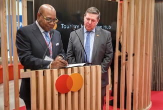 Minister of Tourism, Hon Edmund Bartlett (left), signs a Memorandum of Understanding (MOU) on Tourism Innovation with Senior Vice President, Government Engagement, Latin America and Caribbean, Mastercard, Darren Ware, at the international trade show, FITUR, in Spain, on January 19.