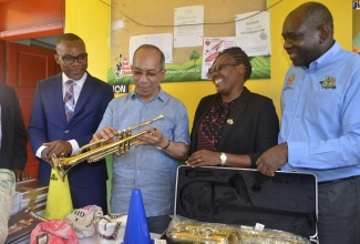 Deputy Prime Minister and Minister of National Security, Hon. Dr. Horace Chang (second left), examines a trumpet that was among the musical instruments and sports equipment donated to Grange Hill High School in Westmoreland under the Ministry’s ‘Liv Gud’ Music, Sports and Technology (MST) initiative. The provisions were handed over on February 10. Sharing the moment are (from left) Member of Parliament, Westmoreland Western, Moreland Wilson; the School’s Principal, Trevine Donaldson Lawrence and Permanent Secretary, Ministry of National Security, Courtney Williams.