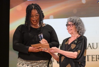 Poet Laureate of Jamaica, Olive Senior (right), makes a presentation to Jenelle Alyssa Samuels, winner of the Poet Laureate of Jamaica Young Writer’s Prize for Poetry. The occasion was the ‘World Poetry Day: Jamaica 60’ celebration held on Tuesday (March 21) at the Little Theatre, 4 Tom Redcam Drive in Kingston.