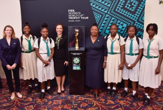 Minister of Culture, Gender, Entertainment and Sport, Hon. Oliva Grange (fourth right), and Foreign Affairs and Foreign Trade Minister, Senator the Hon. Kamina Johnson Smith (fourth left), pose with the original FIFA Women’s Football World Cup Trophy. The occasion was the unveiling ceremony for the Jamaica leg of the FIFA Women’s Football World Cup Trophy Tour, at The Jamaica Pegasus hotel in New Kingston on Monday (April 17). With them are FIFA Senior Manager, Trophy Tours, Sarah Gandoin (left) and members of the Junior Reggae Girlz team.