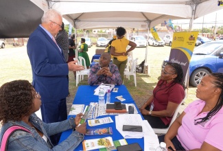 Justice Minister, Hon. Delroy Chuck (left), converses with representatives of the Rural Agricultural Development Authority (RADA) who participated in the Legal Aid Council’s Justice Fair on Friday (March 31). RADA was among several entities mounting booths at the event, which was held in Old Harbour, St. Catherine.