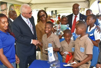 Minister of Justice, Hon. Delroy Chuck (second left), interacts with students of the Lyssons Primary School in St. Thomas during a Justice Fair in the parish on Friday (April 21). Sharing the moment are Chief Justice, Hon. Bryan Sykes (right); Custos Rotulorum for Morant Bay, Hon. Marcia Bennett (second right); and Customer Service Coordinator, Transport Authority, Janet Duffus. The event was held at Rudolph Elder Park in Morant Bay.