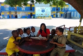 Vice Principal of the Buff Bay Primary School in Portland, Keisha Braimbridge (fourth right), reads to students at the institution.