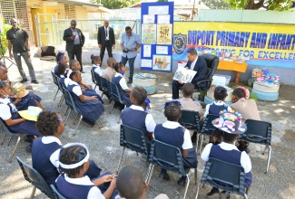 Prime Minister, the Most Hon. Andrew Holness (right, seated), points to illustrations in the book ‘I Can Do My Part’, by Cathryn O’Sullivan, while reading to grade-four students at Dupont Primary and Infant School. The occasion was a visit to the institution, located in his St. Andrew West Central constituency, as part of activities marking Read Across Jamaica Day on Tuesday (May 9).  