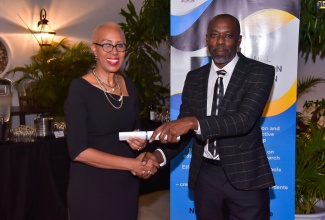 Minister of Education and Youth, Hon. Fayval Williams (left), presents the instrument of office to Chairman of the National Council on Education, Dr. Herbert Gayle. Occasion was a reception of the 24 newly appointed members of the Council held at the Courtleigh Hotel and Suites in Kingston recently. 