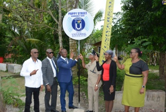 Chief Executive Officer of the Universal Service Fund, Daniel Dawes (second left), participates  in the unveiling of the sign for the Community Wi-Fi at Poppy Street in George’s Plain, Westmoreland, on Wednesday, May 4. He is joined by (from left) Councillor for the Frome Division, Westmoreland, Rudolph Uter; Member of Parliament (MP) for the area, George Wright; Head of the Westmoreland Police Division, Senior Superintendent Wayne Josephs; PRO for Poppy Street PMO Group, Caneisha Myles and Principal for Vision Plus ECI, Marlene Uter. 