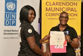 United Nations Development Programme (UNDP) Resident Representative, Denise E. Antonio (right), presents graduate from the Women’s Economic Empowerment Programme, Andre-Lee Mason, with a certificate of participation, during a graduation ceremony held on May 25, at the Wembley Centre of Excellence in Clarendon. The Women’s Economic Empowerment Programme is facilitated under the European Union (EU)/United Nations Spotlight Initiative. A total of 20 survivors of domestic violence graduated.