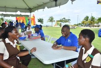 Director of Mental Health and Substance Abuse Services in the Ministry of Health and Wellness, Dr. Kevin Goulbourne (centre), engages grade-nine students, Samoya Graham (left) and Oreanna Morris (right) of Merlene Ottey High School in Hanover, during a child and adolescent mental health playday, held at Harmony Beach Park in Montego Bay, St. James, on Tuesday, May 30.