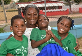 Teacher and mother of triplets, Bridget Thompson-Dunkley, lovingly embraces her children (from left) Jordan, Amanda and Amelia-Rose Dunkley, at the Pembroke Hall Wellness Park in Kingston.