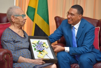 Prime Minister, the Most Hon. Andrew Holness, presents a gift of appreciation to his former English teacher from St. Catherine High School, Valerie Roper, who visited his office on Wednesday (May 10), in recognition of Teachers Day. 