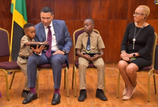 Prime Minister, the Most Hon. Andrew Holness (second left), looks on as six-year-old Ari (left) from the Danny Williams School for the Deaf, signs while using an assistive learning device to read. Also observing are Minister of Education and Youth, Hon. Fayval Williams (right),  and student, Mico University College, Special Education Unit, Nathaniel Campbell. Occasion was a courtesy call at Jamaica House on May 30, to present the Accessible Digital Textbook Project to the Prime Minister. The initiative is a collaboration between the United Nations Children’s Fund (UNICEF) and Book Fusion, to provide children with access to high-quality, interactive digital textbooks in a variety of languages, including Jamaican Sign Language.

