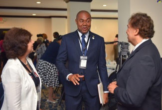 Executive Director, Financial Services Commission (FSC), Major Keron Burrell (centre), converses with (from left) Senior Programmes Director, Toronto Centre, Shelina Visram and Senior Partner, TELUS Health, Al Kiel. Occasion was the opening ceremony for the Caribbean Association of Pensions Supervisors (CAPS) Conference at The Jamaica Pegasus hotel in New Kingston on Tuesday (June 13). 