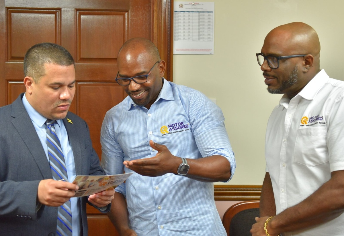 Minister without Portfolio in the Ministry of Economic Growth and Job Creation, Senator the Hon. Matthew Samuda (left) looks at a Motor Assured Limited brochure being shown to him by Chief Executive Officer and President, Xavier Allen,  during a courtesy call at the Ministry in Kingston on June 13. Looking on is Vice President of Special Projects and Marketing, Onel Williams.

