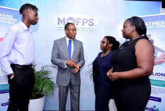 Minister of Finance and the Public Service, Dr. the Hon. Nigel Clarke (second left), interacts with beneficiaries of the Students’ Loan Bureau’s grant-in-aid (from left) Rojay Clarke, Malaka Edwards, and Kaycia Hylton, during the launch of the revised programme at The Jamaica Pegasus hotel in New Kingston on Thursday (July 20).