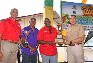 Prime Minister, the Most Hon. Andrew Holness (right), presents the 2023 National Champion Farmer trophy to Managing Director of Unity Boer Goat Farm, Owen Bartley (second right), during the recent staging of the 69th Denbigh Agricultural, Industrial and Food Show at the Denbigh Showground in Clarendon. Sharing the moment (from left) are Vice-President at Hi-Pro, Colonel (Ret’d) Jaimie Ogilvie and Managing Director of the Jamaica Social Investment Fund (JSIF), Omar Sweeney.  