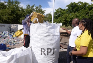 Recycling Partners of Jamaica (RPJ) General Manager, Gairy Taylor (centre), and National Solid Waste Management Authority (NSWMA) Community Relations Manager, Kimberly Blair (right), observe as an RPJ employee deposits plastic bottles into a bag during a cleanup of the New Causeway Fishing Village in St. Catherine on July 5. The NSWMA partnered with RPJ to clear the fishing village of plastic bottles and debris in observance of Plastic Free July.