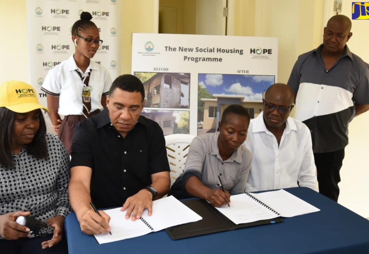 Prime Minister the Most Hon. Andrew Holness (second left), and New Social Housing Programme (NSHP) beneficiary, Georgette Moving (second right), sign the social housing contract outlining her responsibilities as a homeowner under the initiative. Sharing the moment (from left) are Chair, Oversight Committee, NSHP, Judith Robb Walters; Minister without Portfolio in the Ministry of Economic Growth and Job Creation and Member of Parliament, St. Catherine Southwest, Hon. Everald Warmington and (from left, standing) Ms. Moving’s daughter, Janelle Evans and Councillor, Old Harbour North, Keith Knight. Ms. Moving’s new home, which is located in Bamboo Ridge, St. Catherine Southwest, was handed over on Friday (June 23).