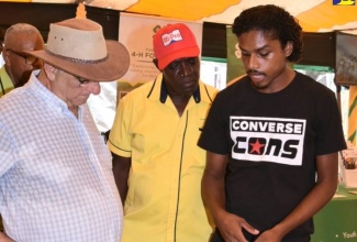 Custos Rotulorum for Clarendon, Hon. William Shagoury (left), listens as Clarendon 4-H Club member Javian Bassier (right), outlines the benefits of a smart irrigation system that he developed, during the 69th Denbigh Agricultural, Industrial and Food Show at the Denbigh Showground in Clarendon on August 6. Also listening is President, Kingston and St. Andrew Association of Branch Societies of the Jamaica Agricultural Society (JAS), Albert Green.