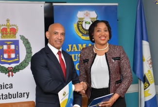 Commissioner of Police, Major General Antony Anderson (left), and Jamaica Customs Agency (JCA) Chief Executive Officer and Commissioner of Customs, Velma Ricketts Walker (right), display signed copies of the Memorandum of Understanding (MOU) to facilitate direct access to the information system of the International Criminal Police Organization (INTERPOL) by the JCA. The signing of the MOU took place at the JCA’s Head Office in Kingston on Tuesday (July 25).