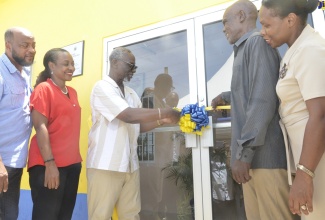 Minister of Local Government and Community Development, Hon. Desmond McKenzie (centre), cuts the ribbon to officially open the Ocho Rios Night Shelter in St. Ann on Friday (August 18). Also taking part in the official opening are (from left), Councillor for the Ocho Rios Division, Michael Belnavis; Member of Parliament for Northeast St. Ann, Hon. Marsha Smith; beneficiary, Byron Gilzene and Permanent Secretary in the Ministry of Local Government and Community Development, Marsha Henry-Martin.