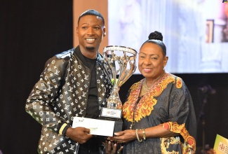 Minister of Culture, Gender, Entertainment and Sport, Hon. Olivia Grange, presents the 2023 Jamaica Gospel Star winner, Oral Lawson, with the trophy at the grand finals of the Jamaica Cultural Development Commission (JCDC)-organised competition, which was held on August 2 at the National Arena.