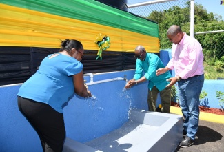 Minister of Local Government and Community Development, Hon. Desmond McKenzie (centre) and Councillor for the John's Hall Division, Faith Sampson (left), wash their hands at the water shop located at Somerset in Manchester on July 7. Looking on is Member of Parliament for North West Manchester, Mikael Phillips.