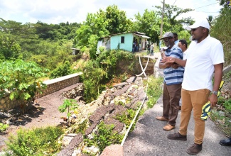 Minister of Local Government and Community Development, Hon. Desmond McKenzie (left), and Minister without Portfolio in the Office of the Prime Minister with Responsibility for Information and Clarendon North Central Member of Parliament, Hon. Robert Morgan, view a breakaway along a road in the community of Suttons during a tour of the constituency on Thursday (August 24).