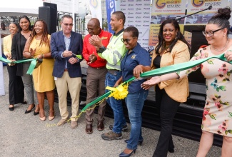 Minister of Science, Energy, Telecommunication and Transport, Hon. Daryl Vaz (fourth left), participates in the cutting of ribbon to officially open the Grennell’s Driving School Crash Free Defensive Driving Workshop and Expo held on Wednesday (June 28), at S Foods Supermarket Parking Lot in New Kingston. He is joined by Director of Grennell’s Driving School, Alphanso Grennell (fifth left) and representatives of corporate sponsors of the event.