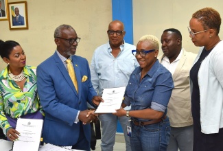 Minister of Local Government and Community Development, Hon. Desmond McKenzie (second left), hands over the contract for the upgrade of Hill Sixty Road in Cheswick, St. Thomas, to Director, FSC Construction Works Limited, Karen Cameron (third right). The signing ceremony for the $12.8-million project took place at the Ministry’s Hagley Park Road offices in St. Andrew on July 18. Others sharing in the moment (from left) are Member of Parliament, St. Thomas Eastern, Dr. Michelle Charles; Councillor, Dalvey Division, Michael McLeod; Mayor of Morant Bay, Councillor Hubert Williams and Acting Chief Executive Officer, St. Thomas Municipal Corporation, Tamika Small.