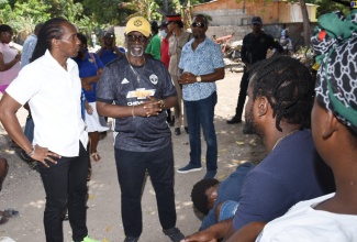 Minister of Local Government and Community Development, Hon. Desmond McKenzie (right) speaks with residents following a tour of the Gregory Park area in St. Catherine, today (August 19). Some 11 houses were firebombed recently, leaving more than 40 persons homeless. Looking on is Member of Parliament for St. Catherine East Central, Hon. Alando Terrelonge (left). The National Solid Waste Management Authority is already undertaking a clean-up exercise in the area.