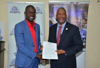 President of the Montego Bay Chamber of Commerce and Industry (MBCCI), Oral Heaven (left), and President of the University of the Commonwealth Caribbean (UCC), Haldane Davies, display a signed memorandum of understanding (MOU) to undertake a crime impact study in Montego Bay, at the Chamber’s offices at Freeport in St. James on Friday, September 22.