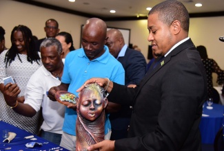Minister of Agriculture, Fisheries and Mining, Hon. Floyd Green (right), admires a sculpture done by Artist and Founder, Khadabra Limited, Robert Campbell (left), during the Organization of African, Caribbean and Pacific States (OACPS)/European Union (EU)/United Nations Development Programme (UNDP) development minerals programme final conference on Wednesday (October 18) at the Jamaica Pegasus Hotel in New Kingston.

