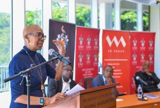 Minister of Education and Youth, Hon. Fayval Williams (at podium), addresses the University of the West Indies (UWI) Colloquium on Financing Tertiary Education, held at UWI’s Regional Headquarters in Kingston on Wednesday (October 11). Looking on (seated from left) are UWI Mona Principal, Professor Densil Williams; President and Chief Executive Officer (CEO) of VM Group, Courtney Campbell; and UWI Vice Chancellor, Professor Sir Hilary Beckles.