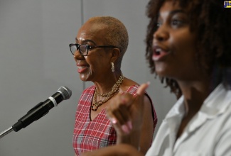 Minister of Education and Youth, Hon. Fayval Williams (left), delivers remarks during Thursday’s (October 12) National Youth Mental Health Summit held at the AC Hotel by Marriott in Kingston. At right is sign language interpreter, Mandy Cowan.