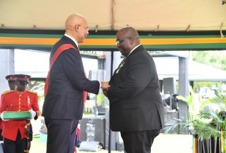 Governor General, His Excellency, the Most Hon. Sir Patrick Allen (left,) presents President of the HELP Jamaica Medical Mission (HELPJaMM), Dr. Robert Clarke, with the Order of Distinction in the rank of Commander (CD) for contribution in the field of Medicine and Philanthropy, during the National Honours and Awards ceremony on October 16 on the lawns of King’s House.

