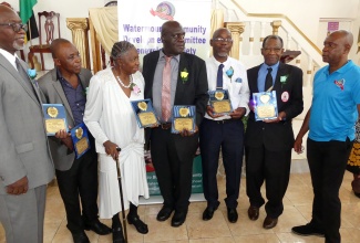 President of the Watermount Community Development Committee (CDC) Benevolent Society in St. Catherine, Carlos McLeod (right), engages with six of the nine ‘community heroes’ who were recently honoured by the CDC, during a ceremony at the Pedro Church of Christ in the parish.