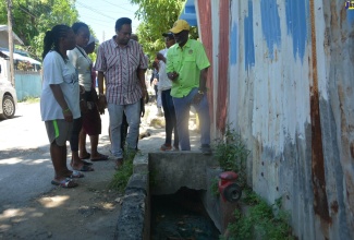 Minister of Local Government and Community Development, Hon. Desmond McKenzie (right), converses with the Ministry’s Chief Technical Director, Dwight Wilson (second right), and residents of Falmouth, Trelawny, where drain cleaning will be carried out to contain the spread of dengue, during a visit on Friday (October 6).

